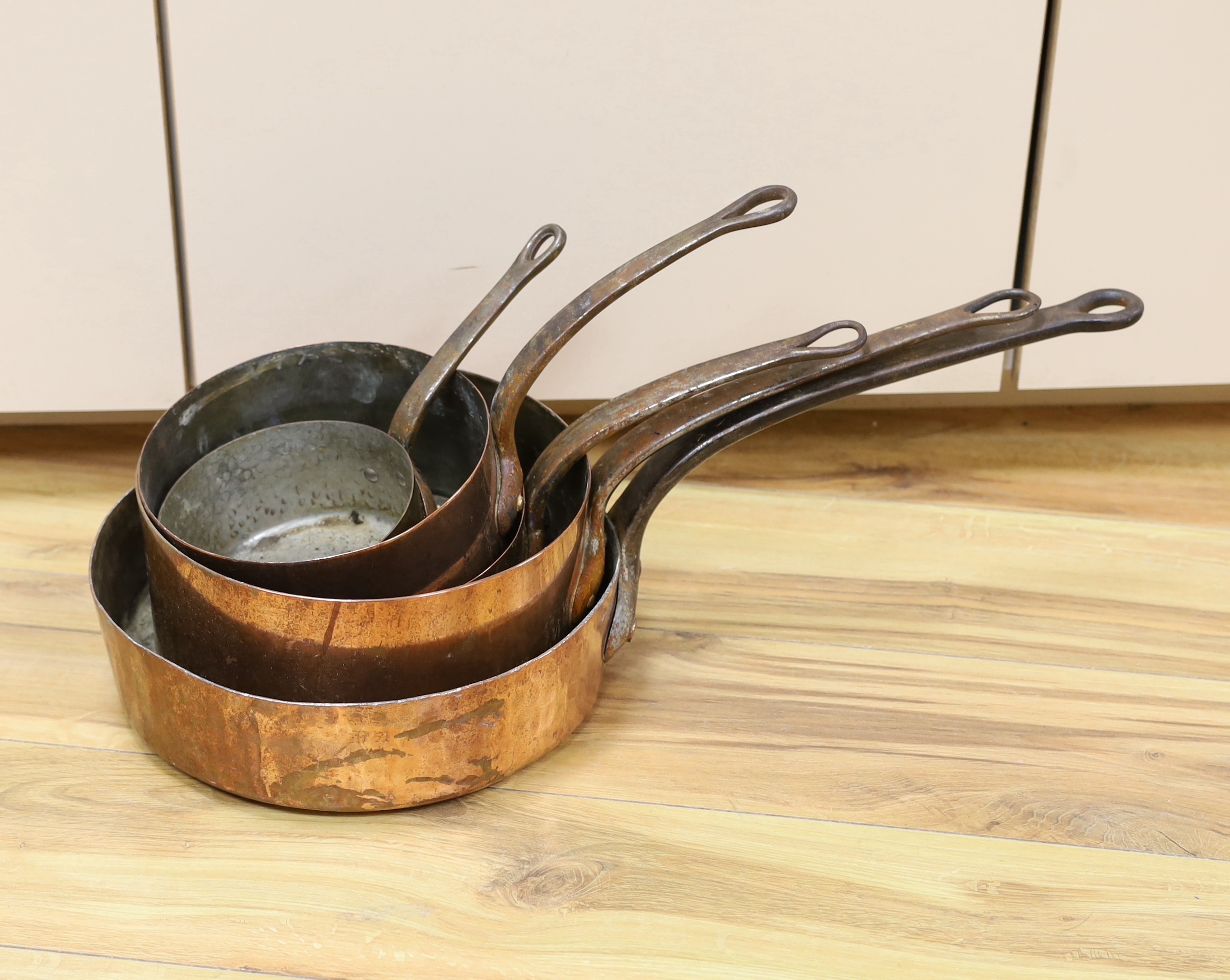 A set of five copper pans, largest diameter 28cm